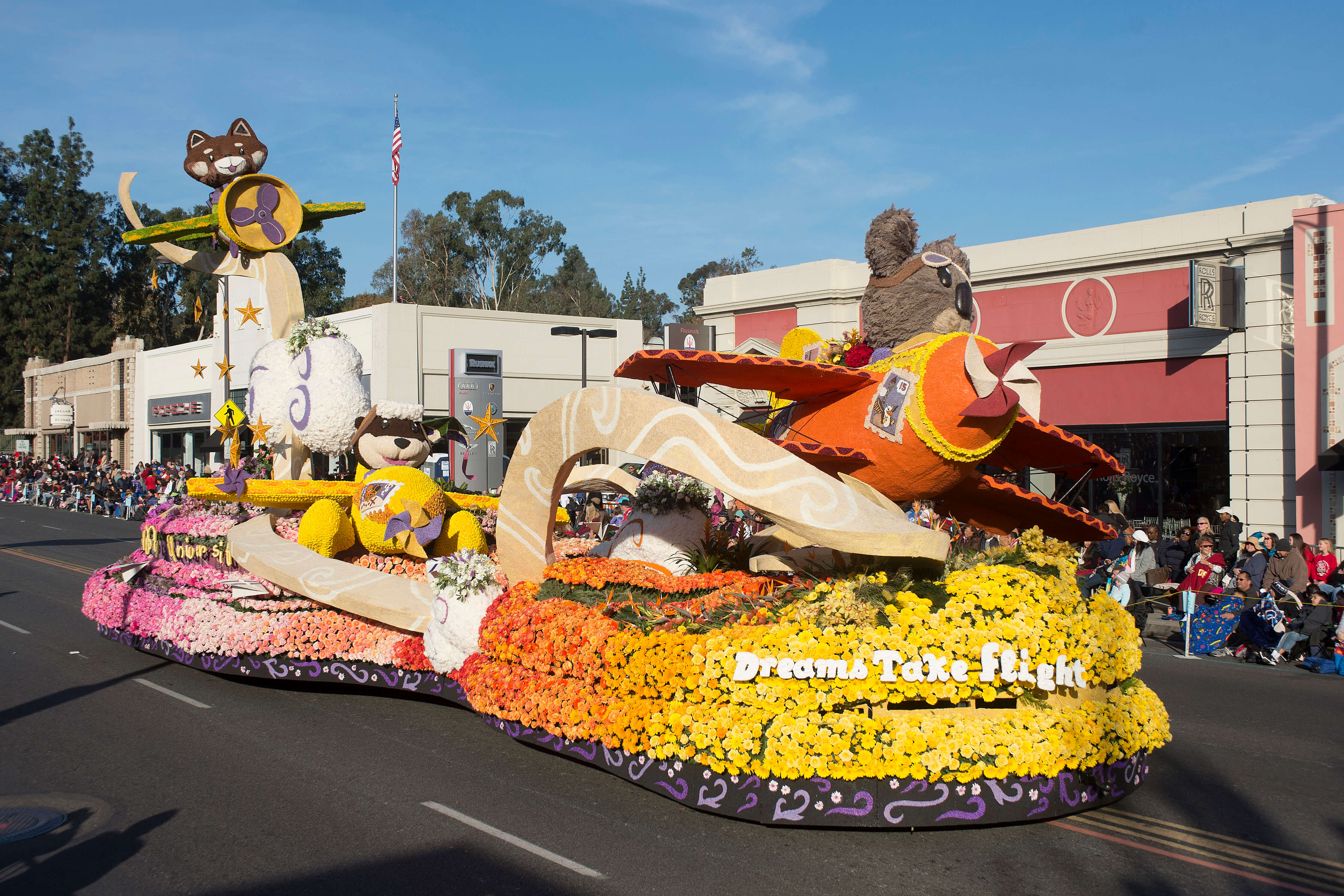 Cal Poly Rose Float's 2019 Float titled Dreams Take Fligh featuring a koala and otter covered in flowers flying airplanes