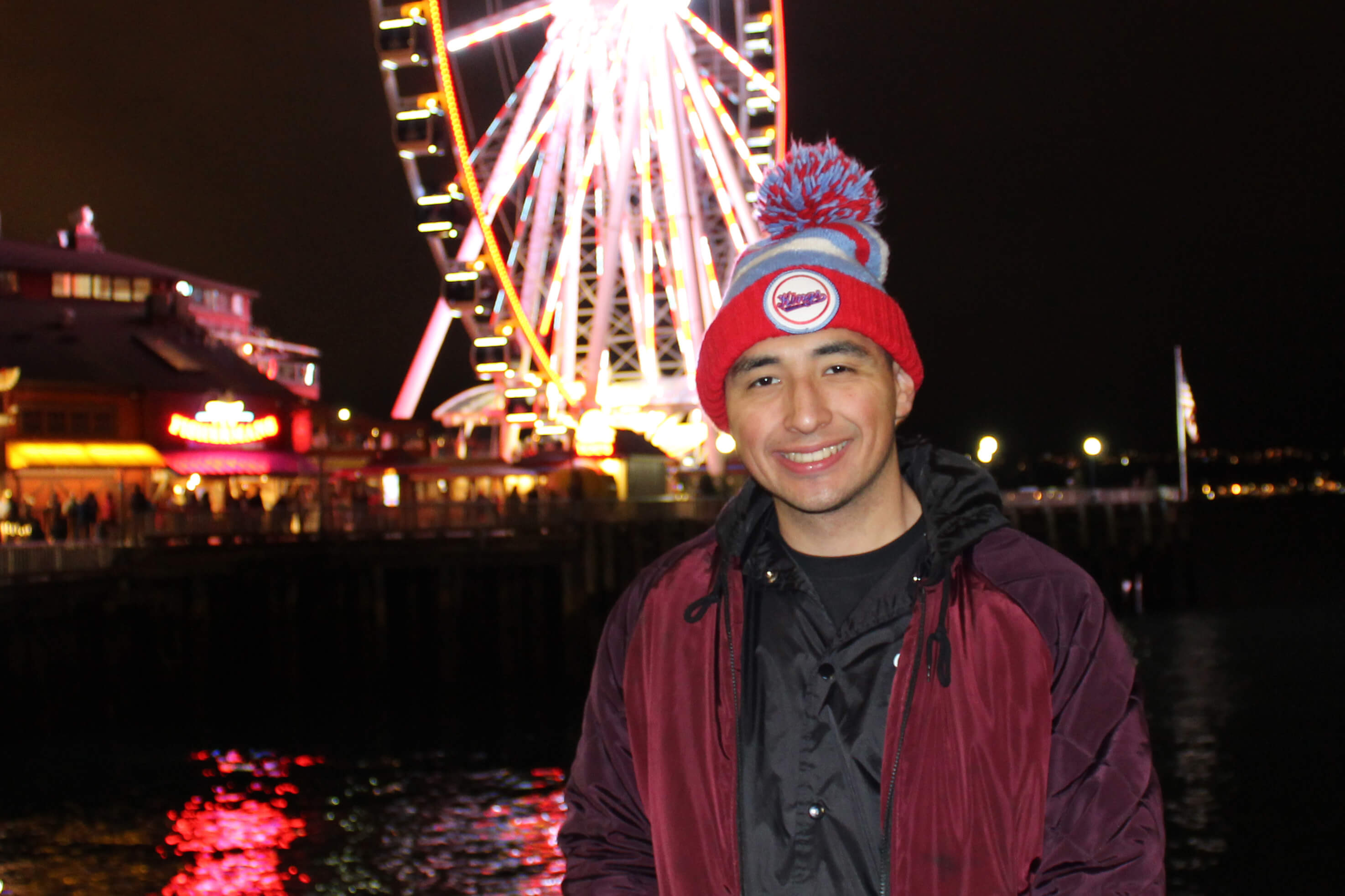 Victor Wilson smiles while standing in front of a ferris wheel at night