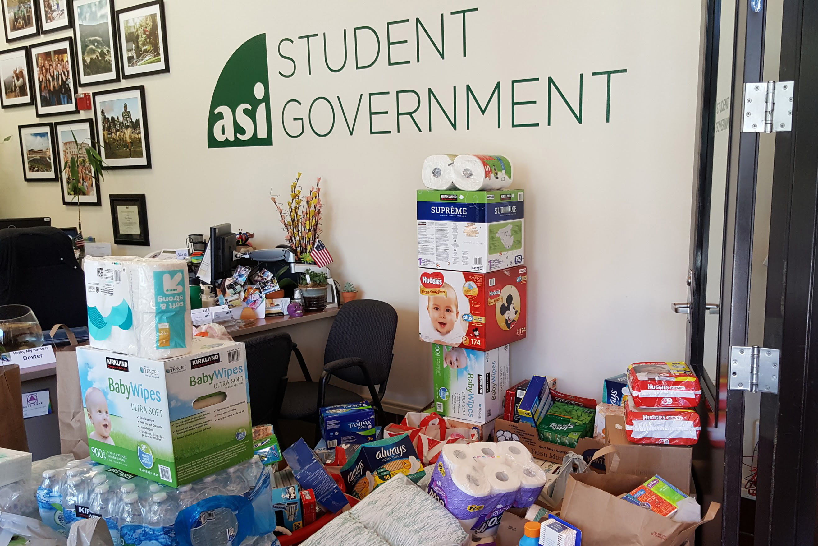Items including water bottles, paper towels, and diapers are piled up in front of the ASI Student Government office